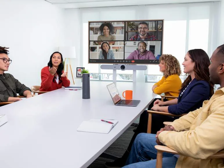 Large conference room with remote participants on a video display