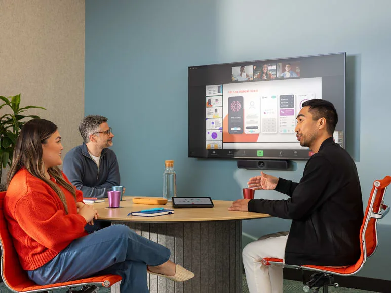 Three colleagues in a small meeting room during a video call